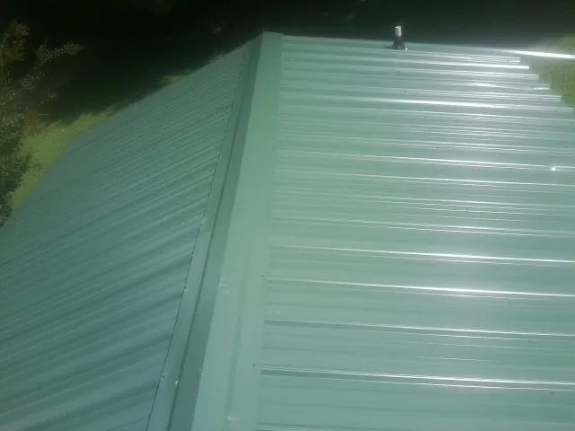 New green metal panels meeting at the ridge of a roof — Flat Roof Repair work by our crew in Tiptonville