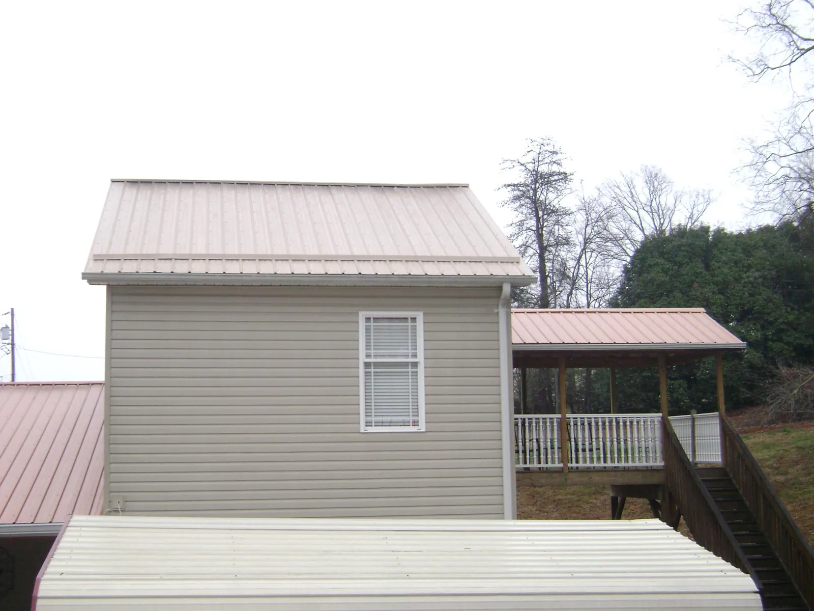 Tan metal roofs on a two story addition and attached porch, from a Roof Replacement job in Tiptonville