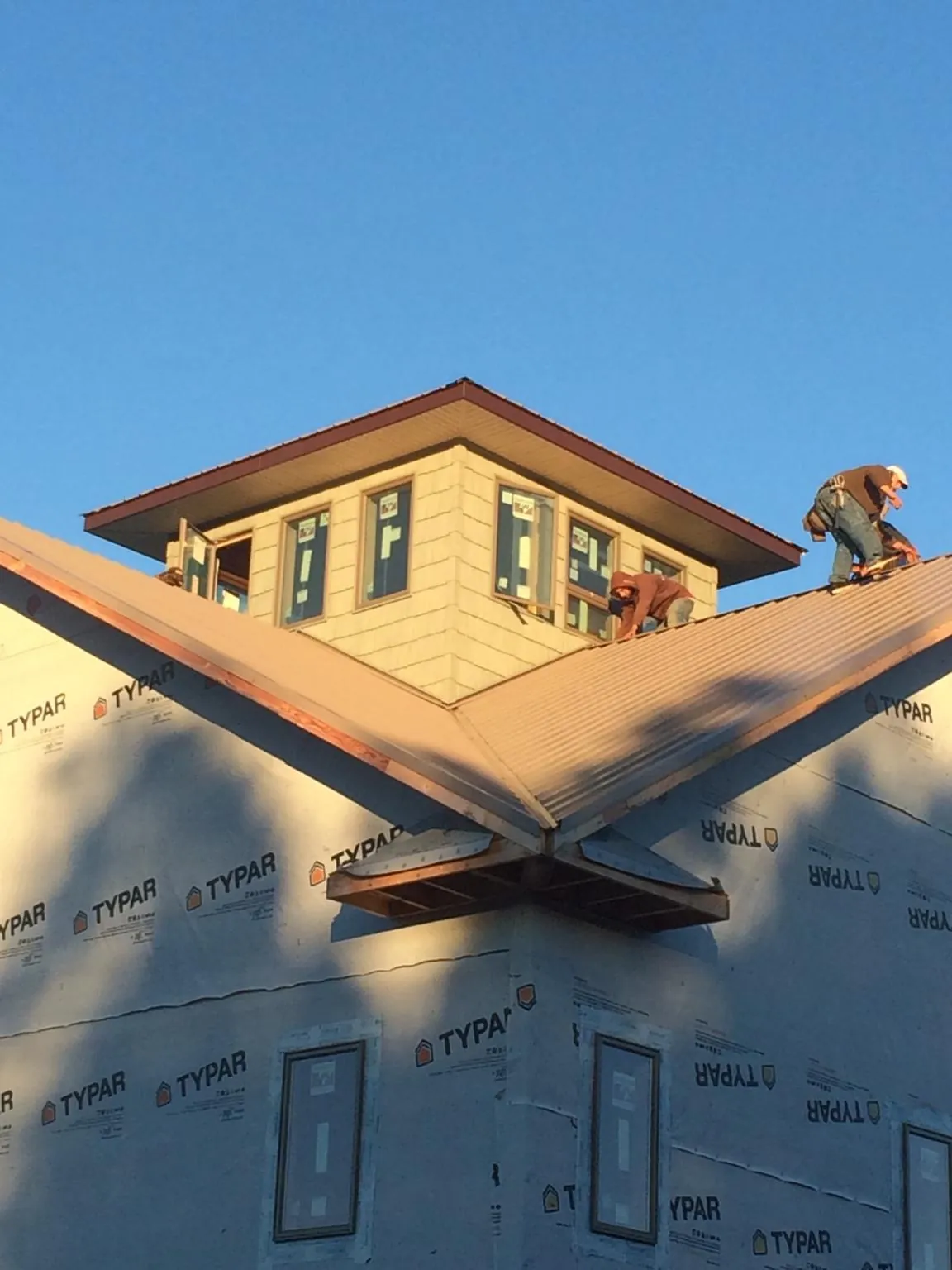 Roofers working around a rooftop cupola on a new metal roof at sunset — Roof Waterproofing in Tiptonville by Roofing Brothers